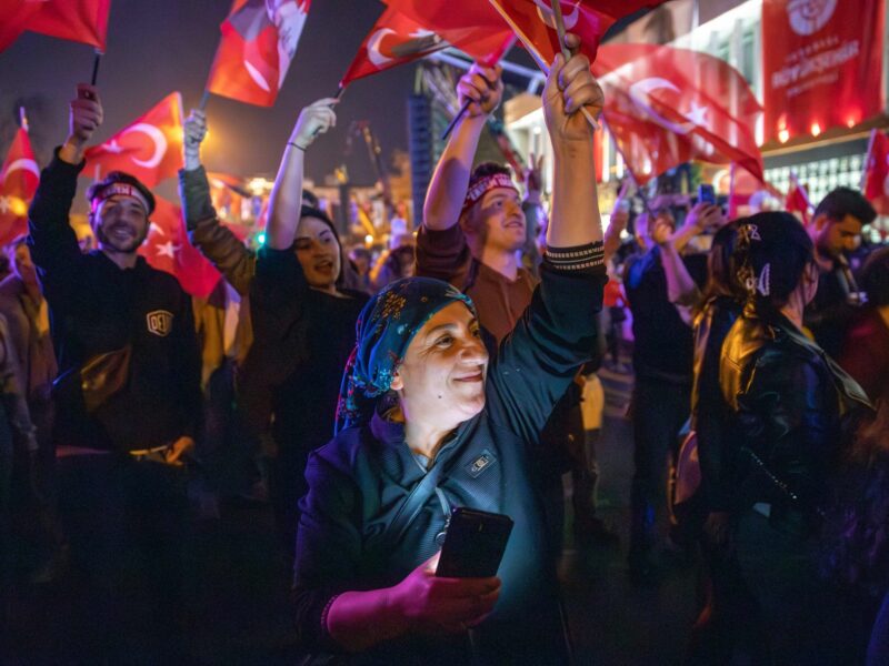 Photo of a woman waving a flag and holding a smartphone