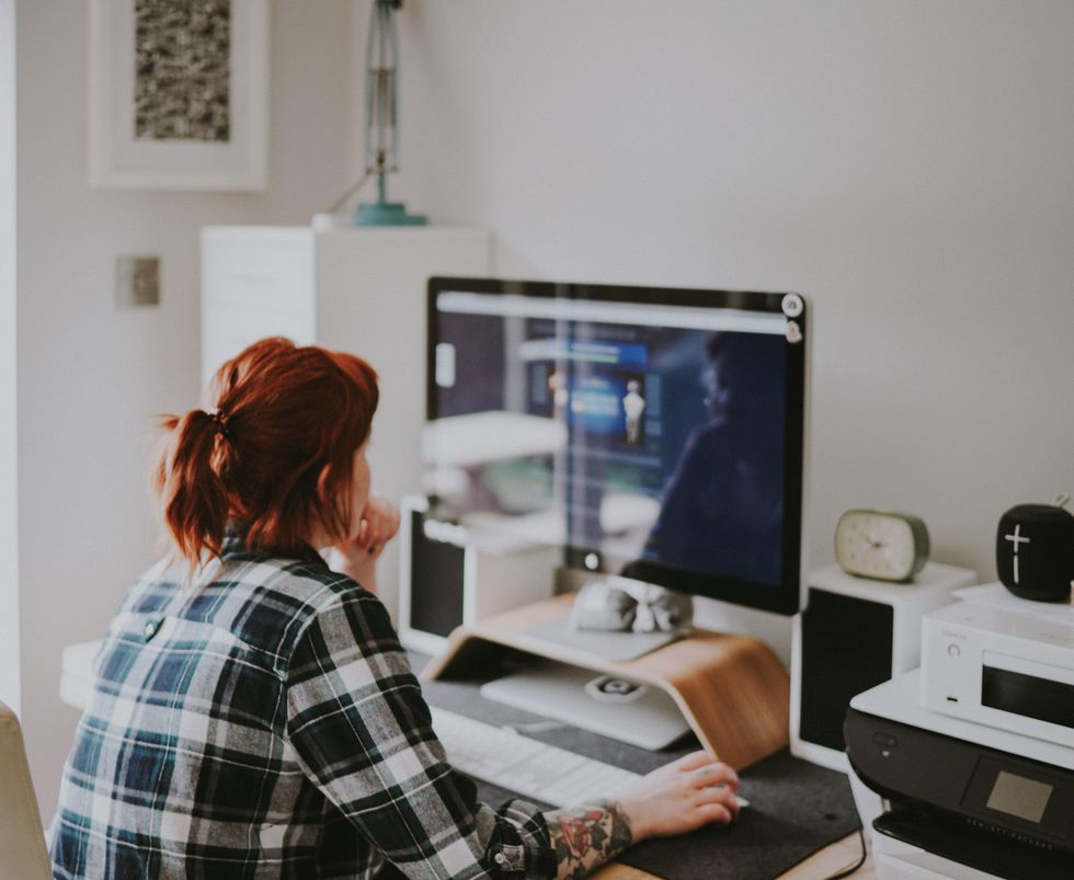 Photo of a woman wearing a flannel shirt working on her computer at home