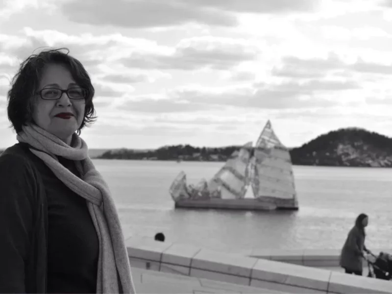 Photo of a woman with a boat behind her.