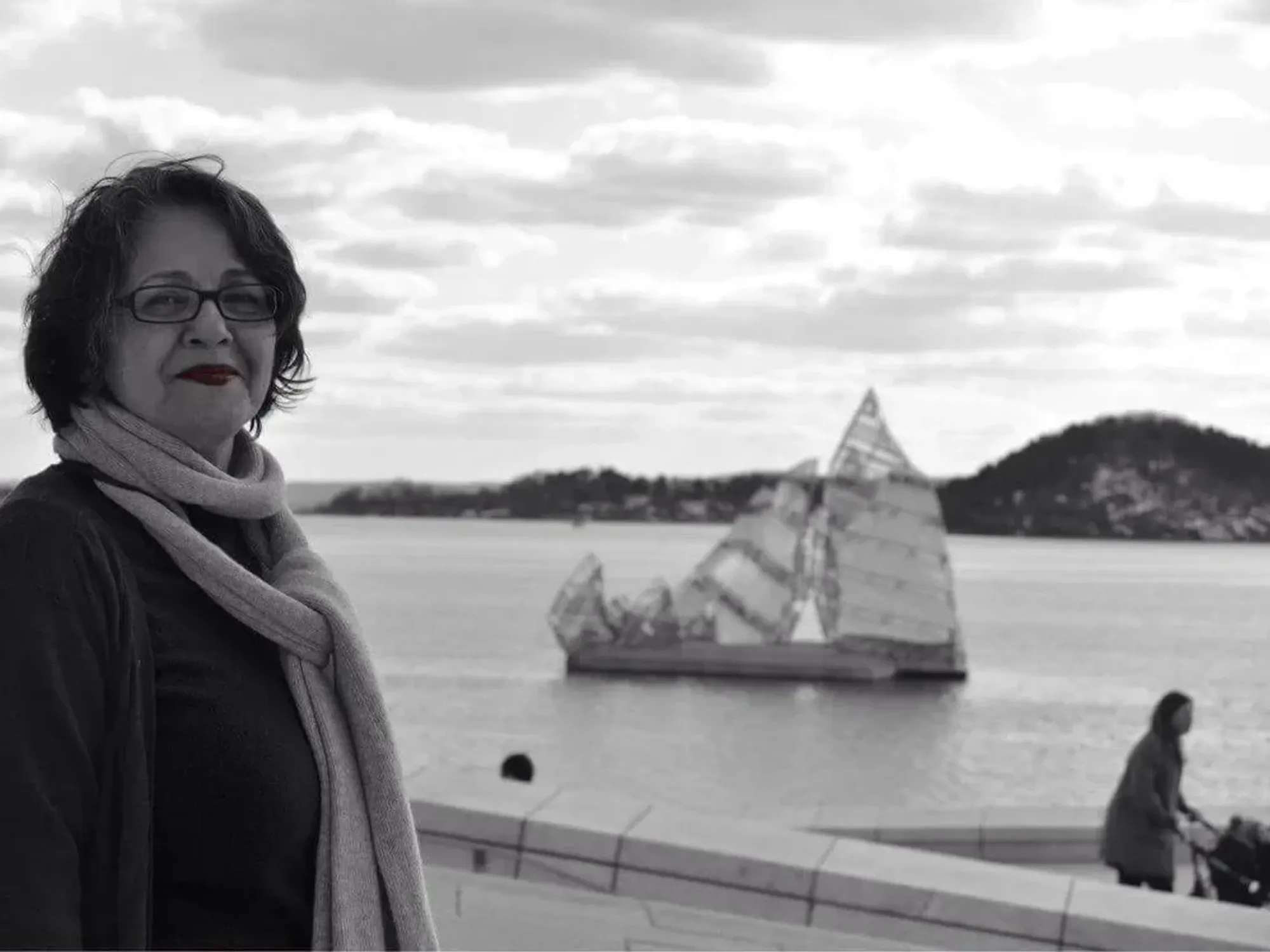 Photo of a woman with a boat behind her.