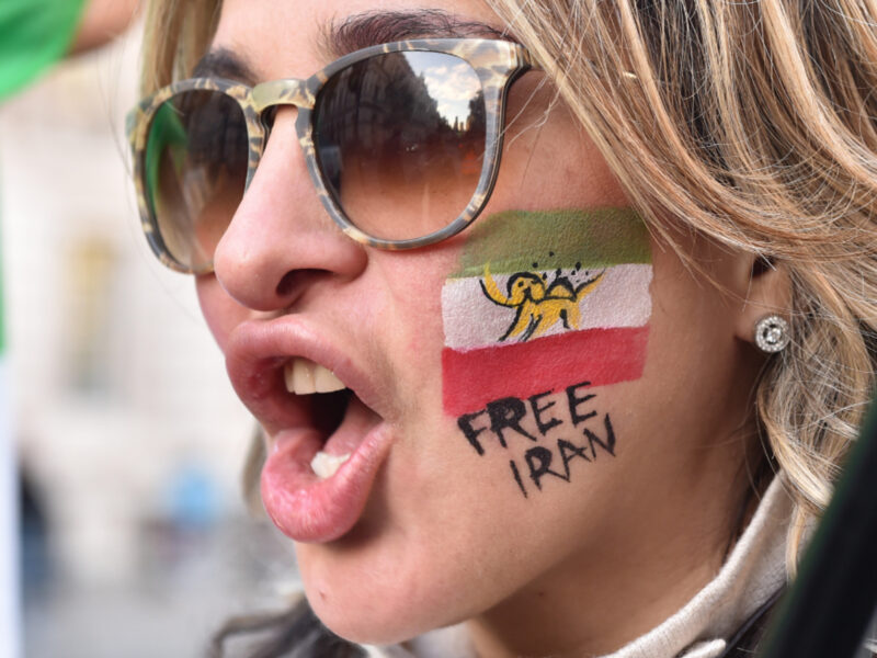 Photo of a woman with a flag of Iran and the inscription "Free Iran" painted on her face