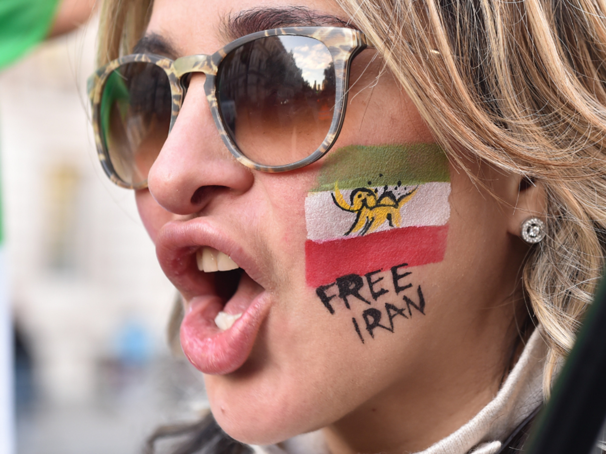 Photo of a woman with a flag of Iran and the inscription "Free Iran" painted on her face