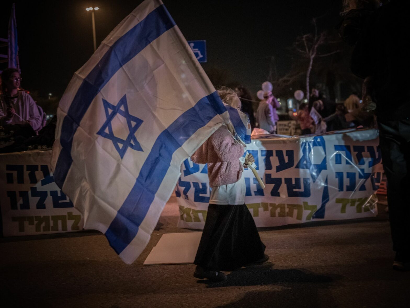 Photo of a woman with a giant Israeli flag as part of a protest by Israeli settlers in Tel Aviv on Dec. 26