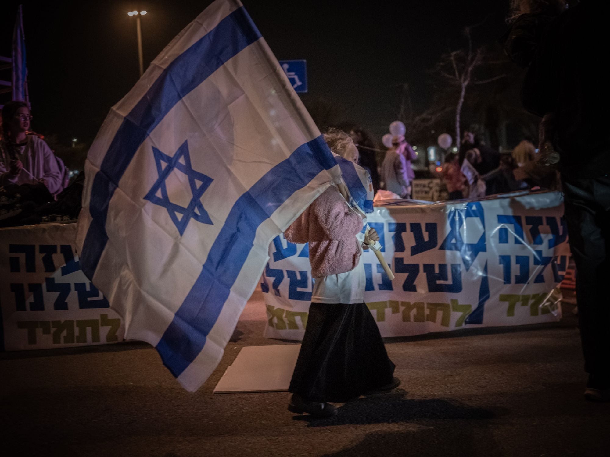 Photo of a woman with a giant Israeli flag as part of a protest by Israeli settlers in Tel Aviv on Dec. 26