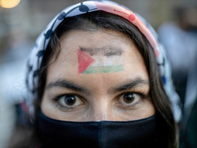 Photo of a woman with a Palestinian flag painted on her face during a rally