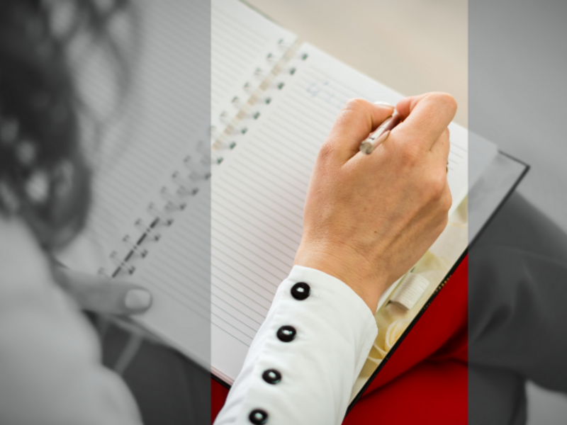 Photo of a woman writing on a notepad
