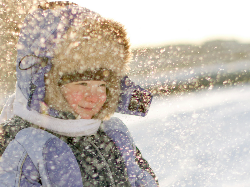 Photo of a young child in a winter coat, with snowflakes blowing by