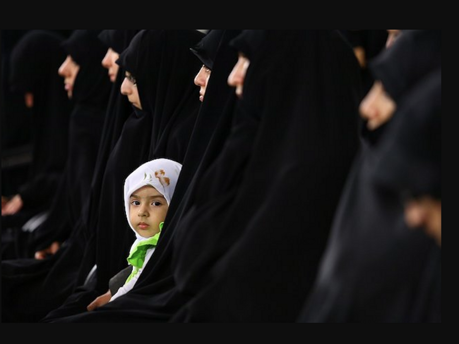 photo of a young child surrounded by women in chadors