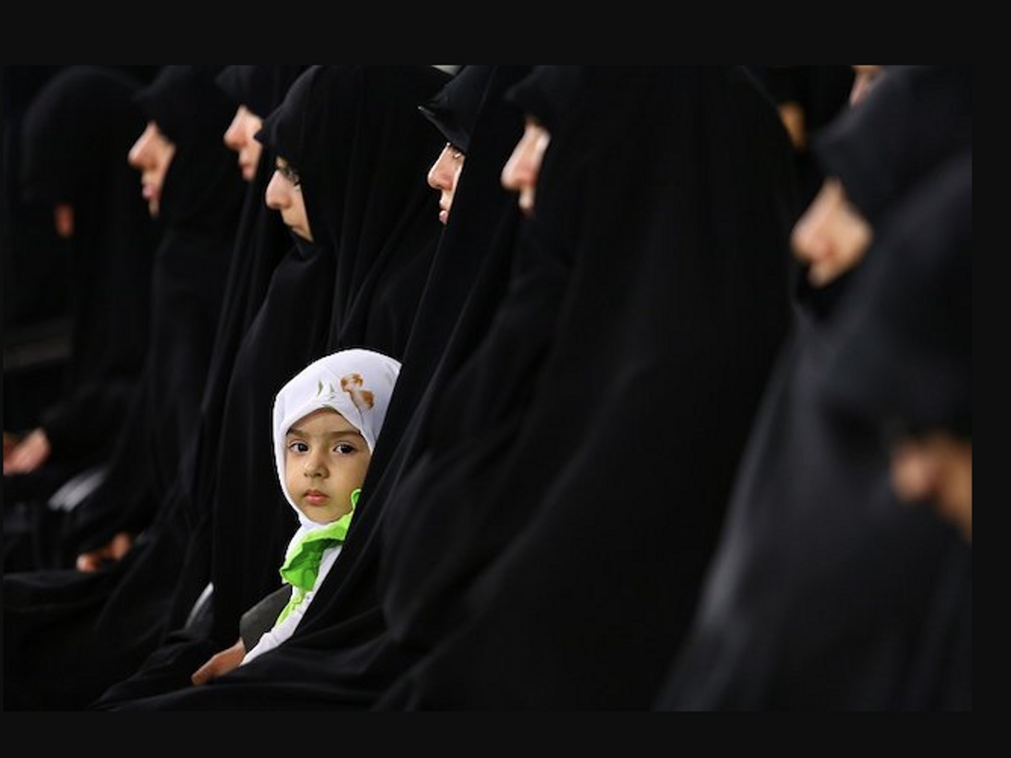 photo of a young child surrounded by women in chadors
