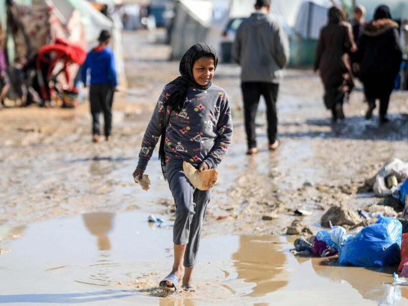 Photo of a young girl walking through rain water at a camp in Gaza
