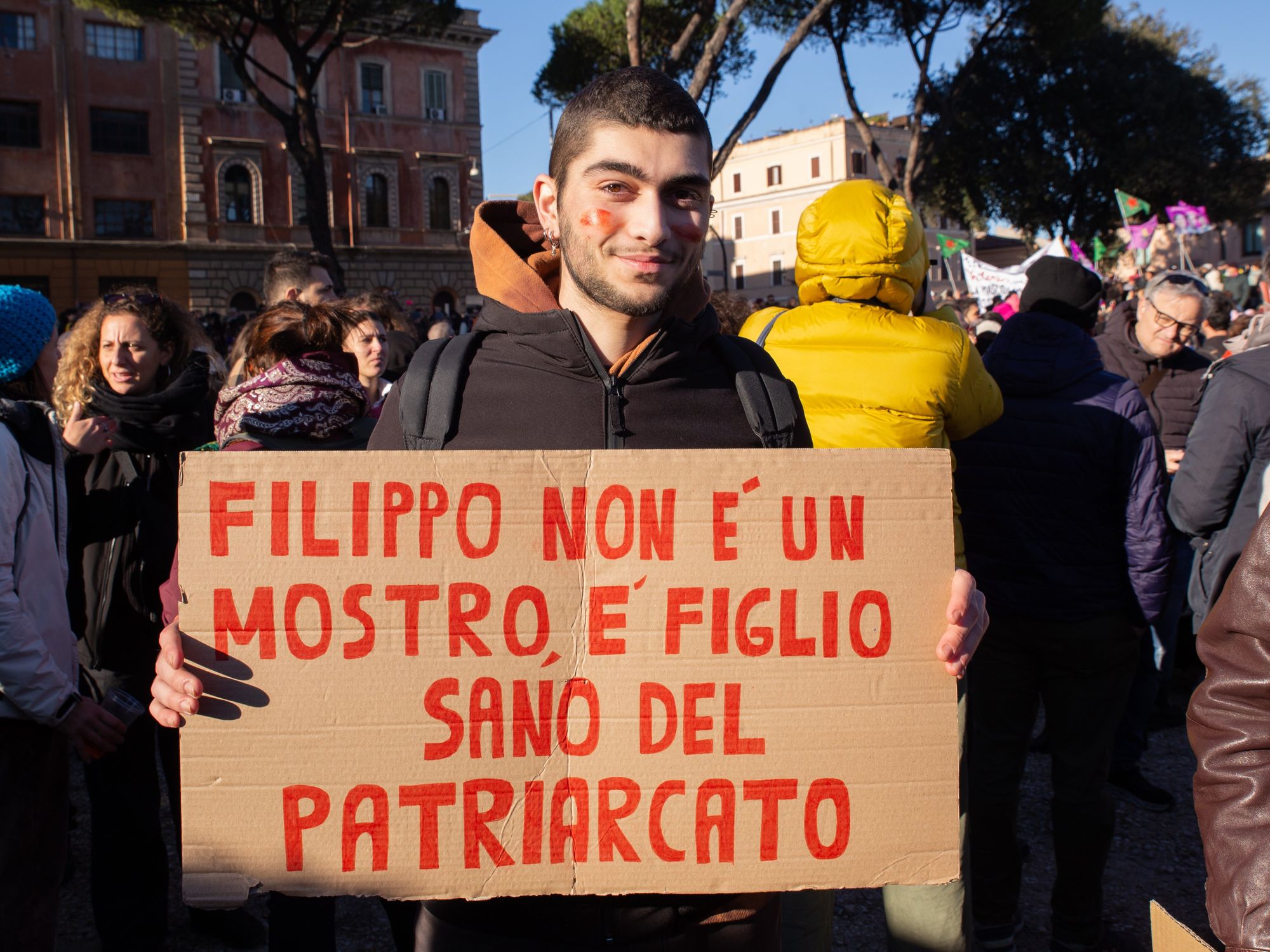 photo of a young man holding a sign: Filippo isn't a monster, he's the healthy son of the patriarchy