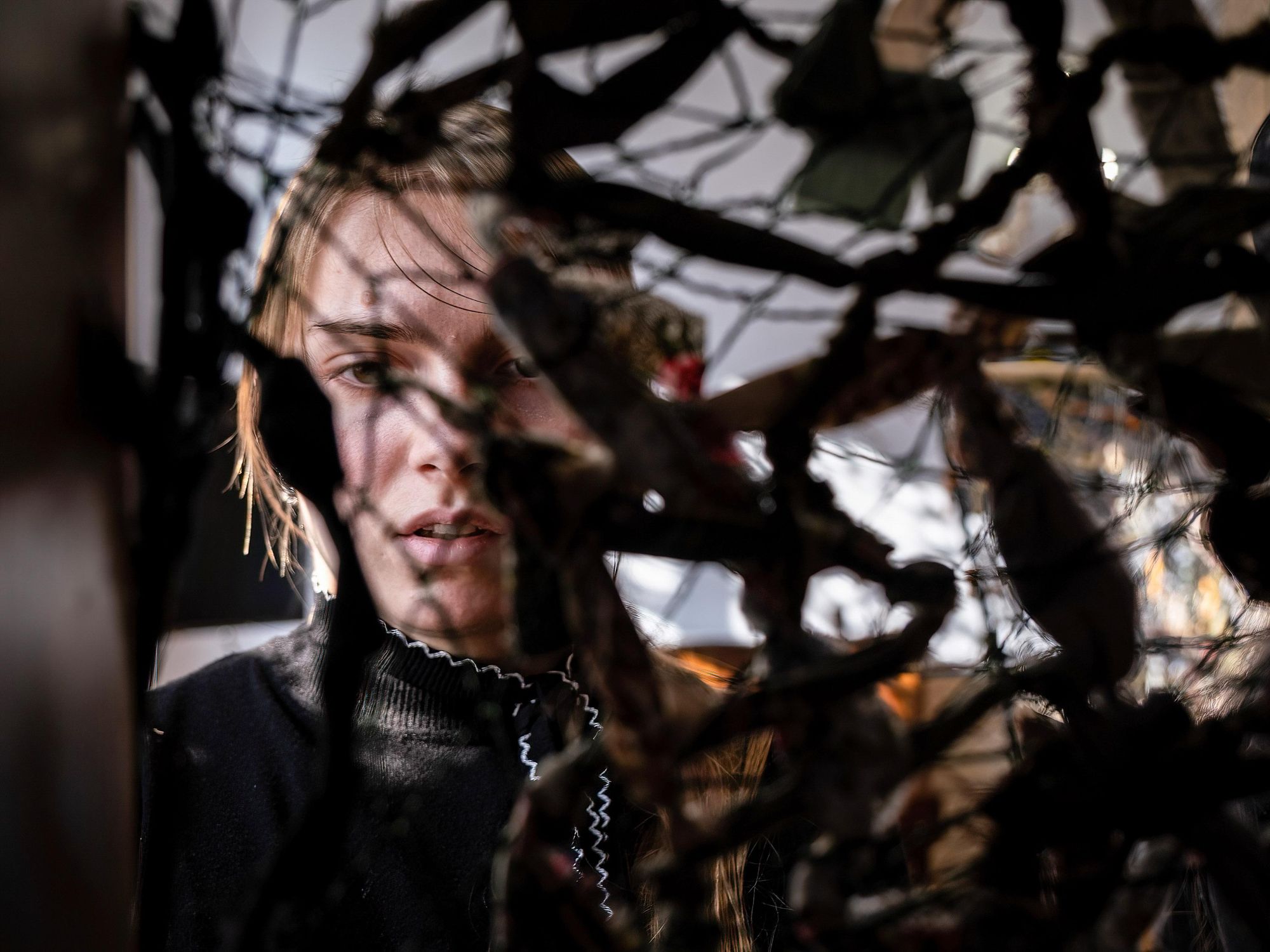 Photo of a young Ukrainian girl looking through camouflage she is knitting for her country's military