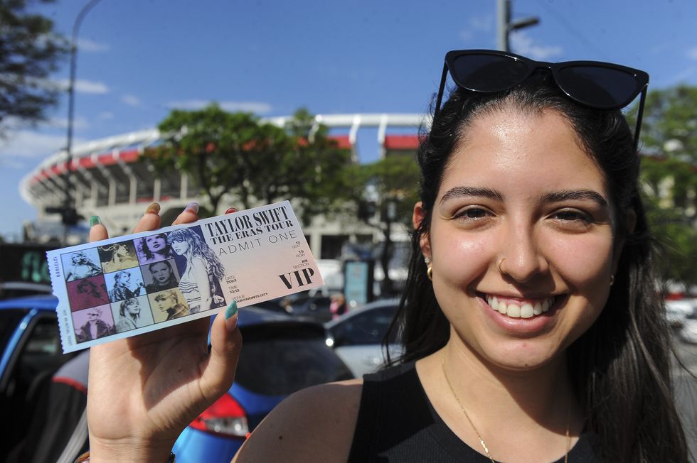 photo of a young woman holding up a ticket in front of a stadium
