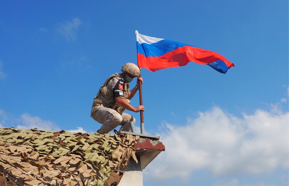 Photo of aA Russian military police officer planting a Russian national flag is seen during a joint patrol of the M4 Motorway with Turkish troops in the Idlib de-escalation zone in northeast Syria, Latakia Province, Syria, July 22, 2020.