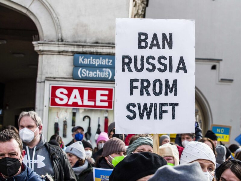 Photo of an anti-Ukraine war protest with a placard that reads "Ban Russia from Swift"