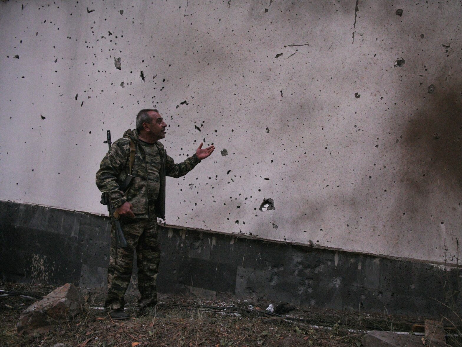 photo of an Armenian soldier looking at a damaged wall.