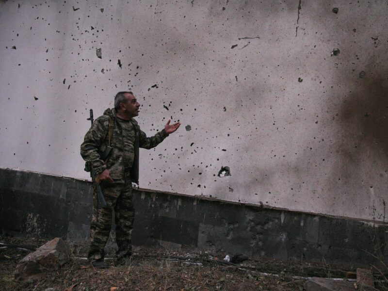 photo of an Armenian soldier looking at a damaged wall.