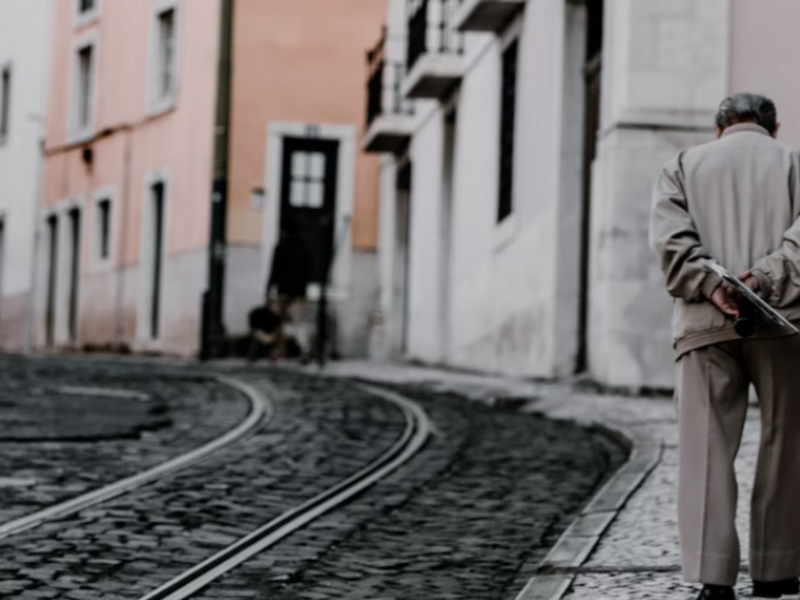 Photo of an elderly man walking near tramway tracks in Lisbon, Portugal