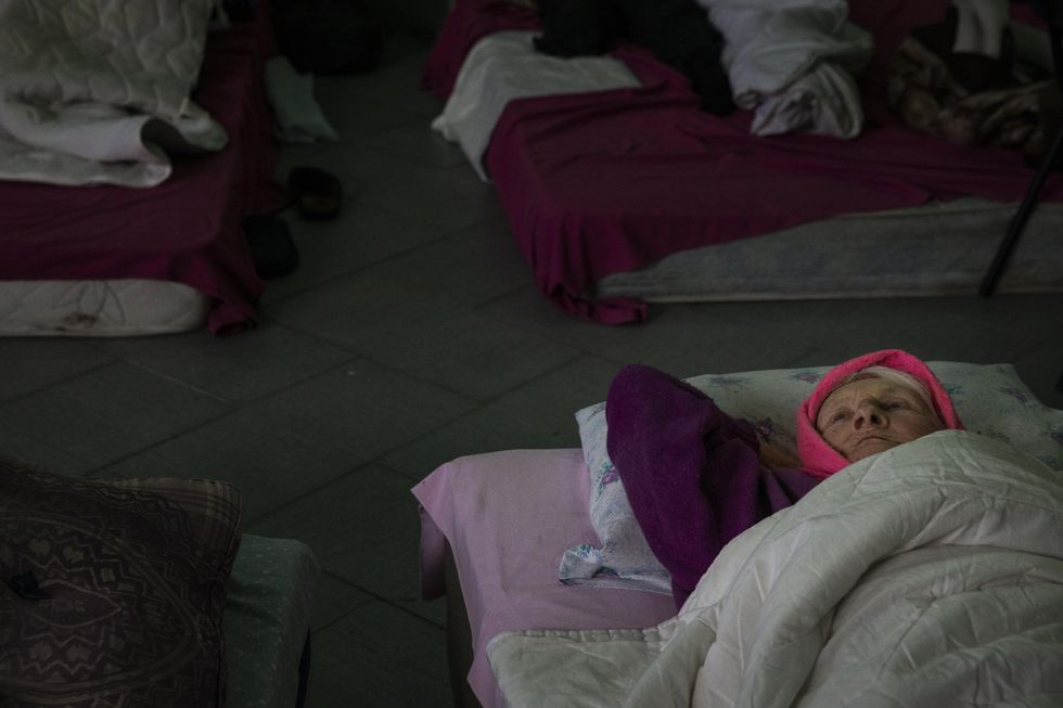 Photo of an elderly woman resting on a mat on the floor before being transported to a train station in Pokrovsk, Ukraine, on April 13, 2022.