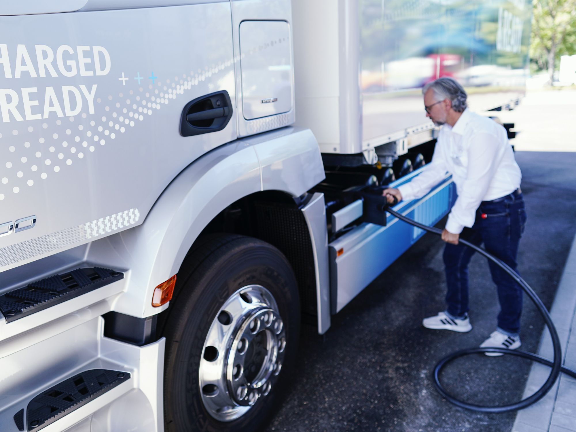 Photo of an employee demonstrating how to charge a truck at the Mercedes-Benz Trucks KundenCenter during the opening of the new Netze BW and Daimler Truck demo charging park in Germany.