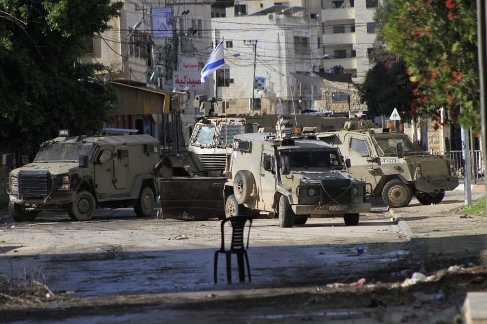 Photo of an empty chair facing IDF vehicles in Jenin, West Bank, on Dec. 14