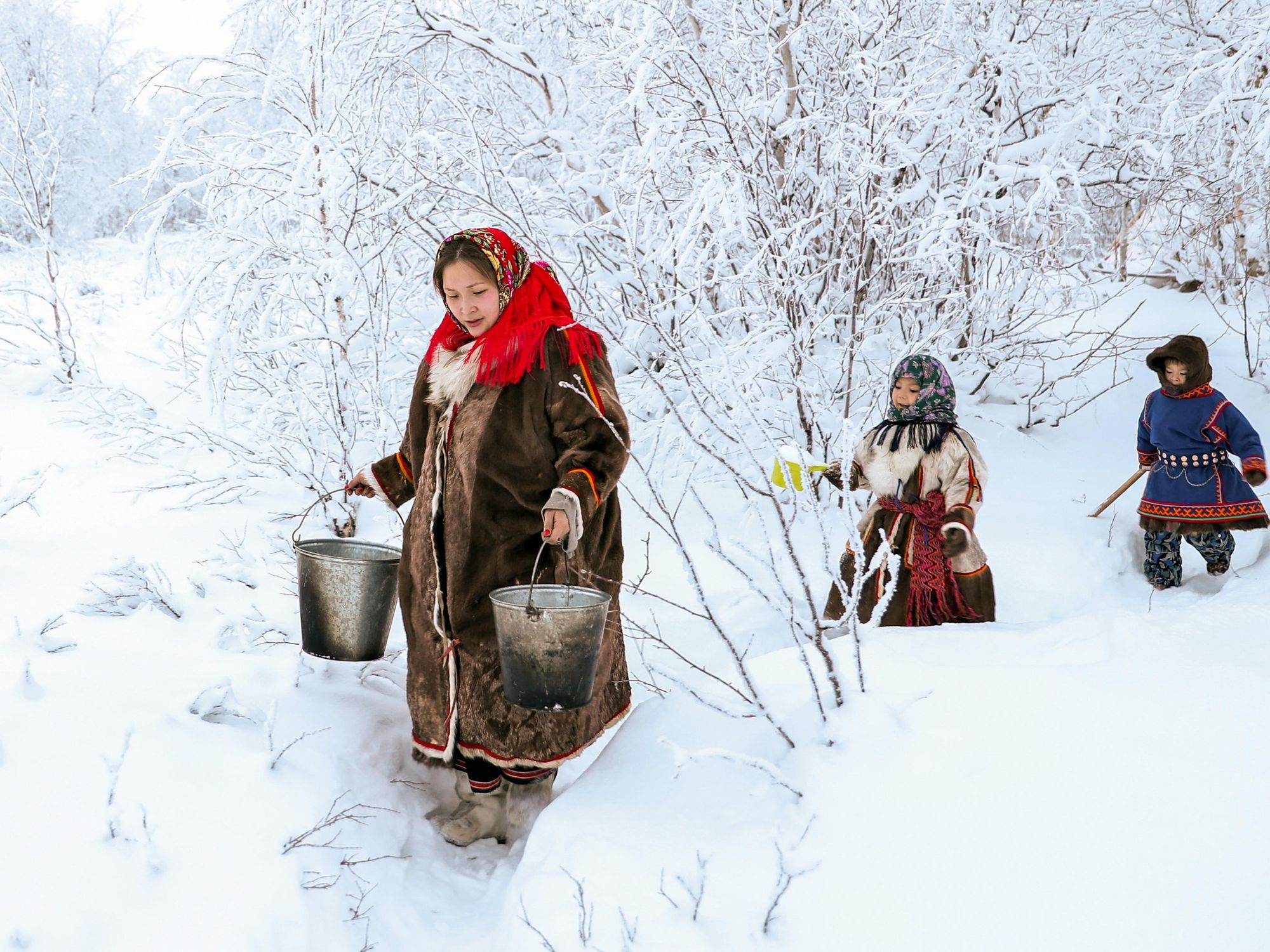 Photo of an indigenous woman with children gathers snow for melting in the Yamalo-Nenets autonomous area of Russia
