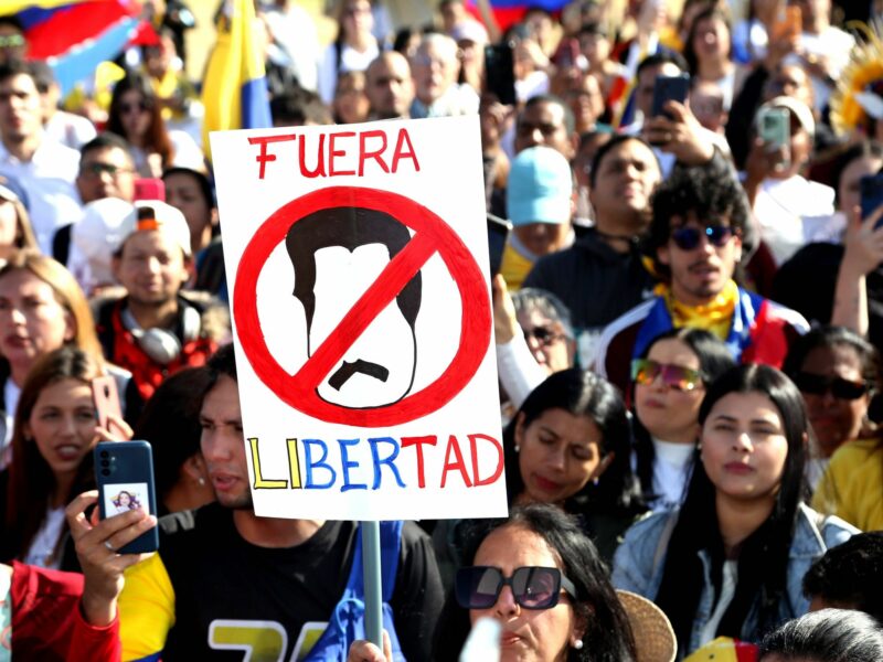 Photo of anti-Maduro protesters in Quito, Venezuela, on August 3, holding a sign with a drawing of a crossed out caricature of president Maduro