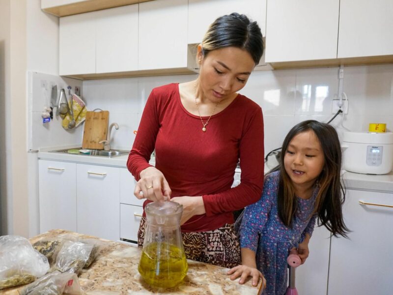 Photo of Bayarjargal Togmid and her 9-year-old daughter, Binderiya Tsendee, steep manjingarav, a local herb, in hot water in their home in Orkhon province, Mongolia.