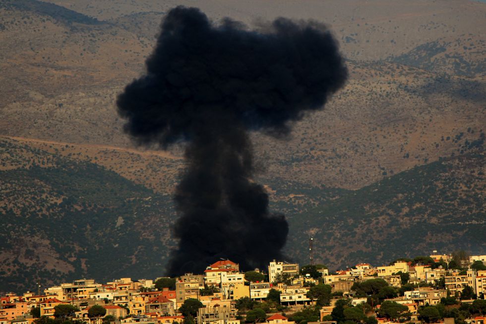 photo of black smoke in a town on a hill