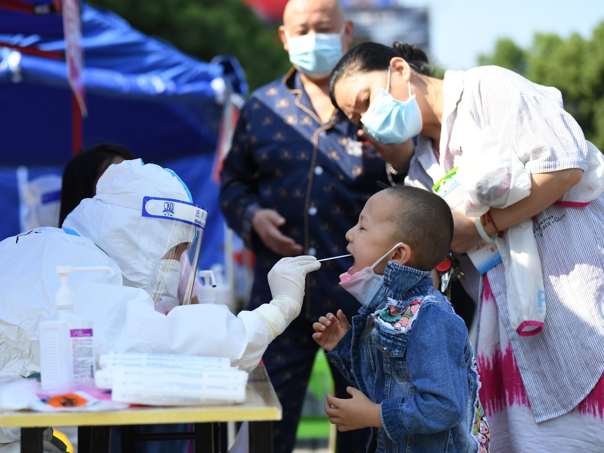 Photo of boy being tested for covid by man in hazmat suit