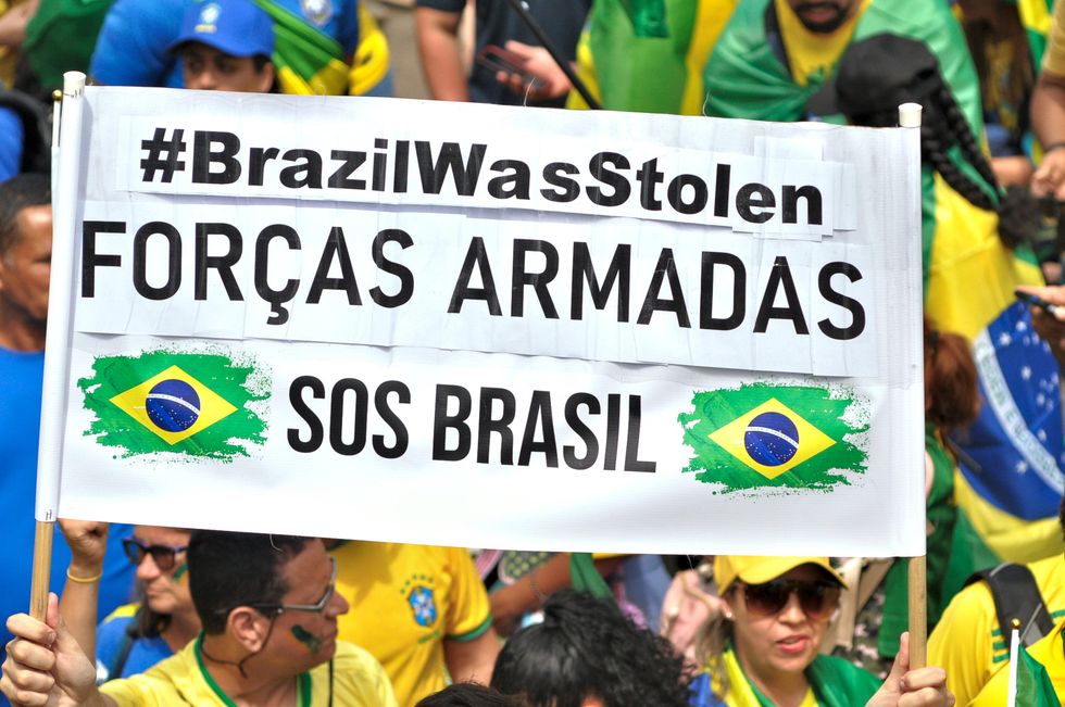Photo of Brazilian supporters of President Jair Bolsonaro holding up a sign SOF Brasil inRio de Janeiro