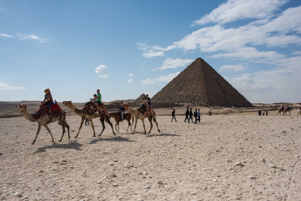 Photo of camels and tourists in front of the Menkaure Pyramid in Giza, Egypt