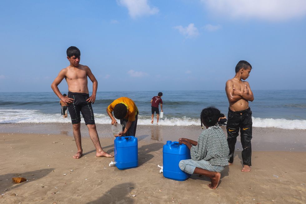 Photo of children on the beach filling gallons up with seawater