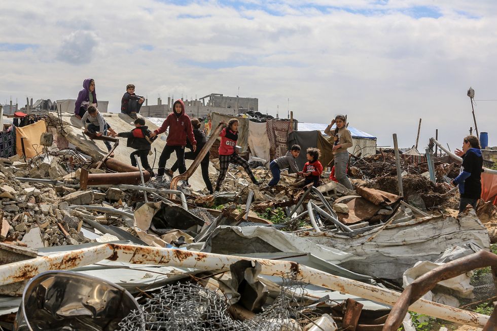 Photo of children walking on rubble in Gaza.