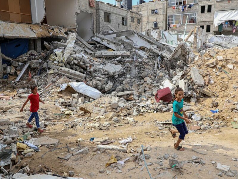 Photo of children walking past a building destroyed in Israeli airstrikes in Khan Younis, southern Gaza, on Oct. 16