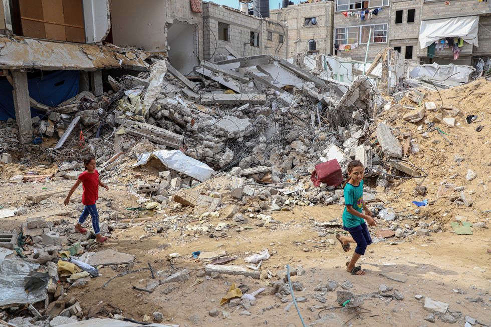 Photo of children walking past a building destroyed in Israeli airstrikes in Khan Younis, southern Gaza, on Oct. 16