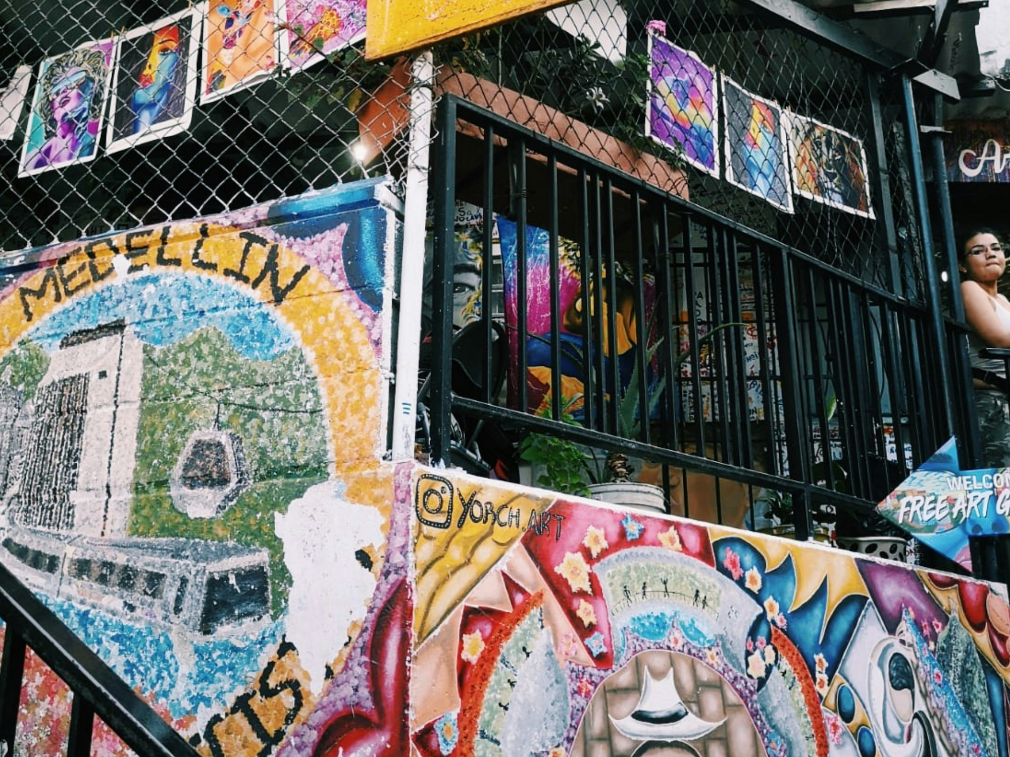 Photo of colorful street art in Medellín, Colombia, with a local woman looking on