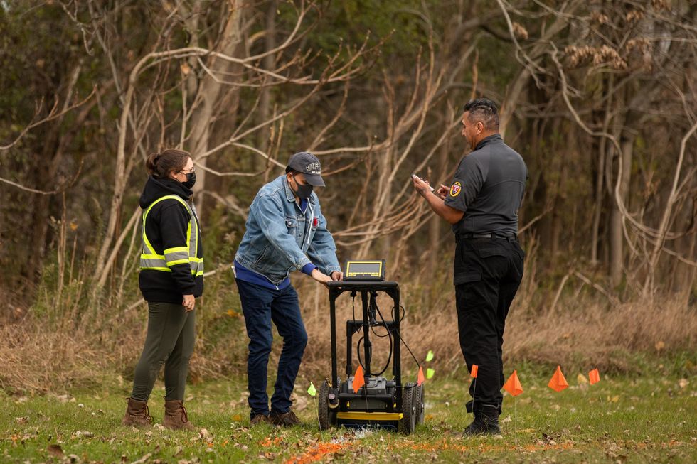 Photo of community members and Six Nations police using radar technology used on the grounds of the former Indian Residential School, the Mohawk Institute, in Brantford, Ontario.