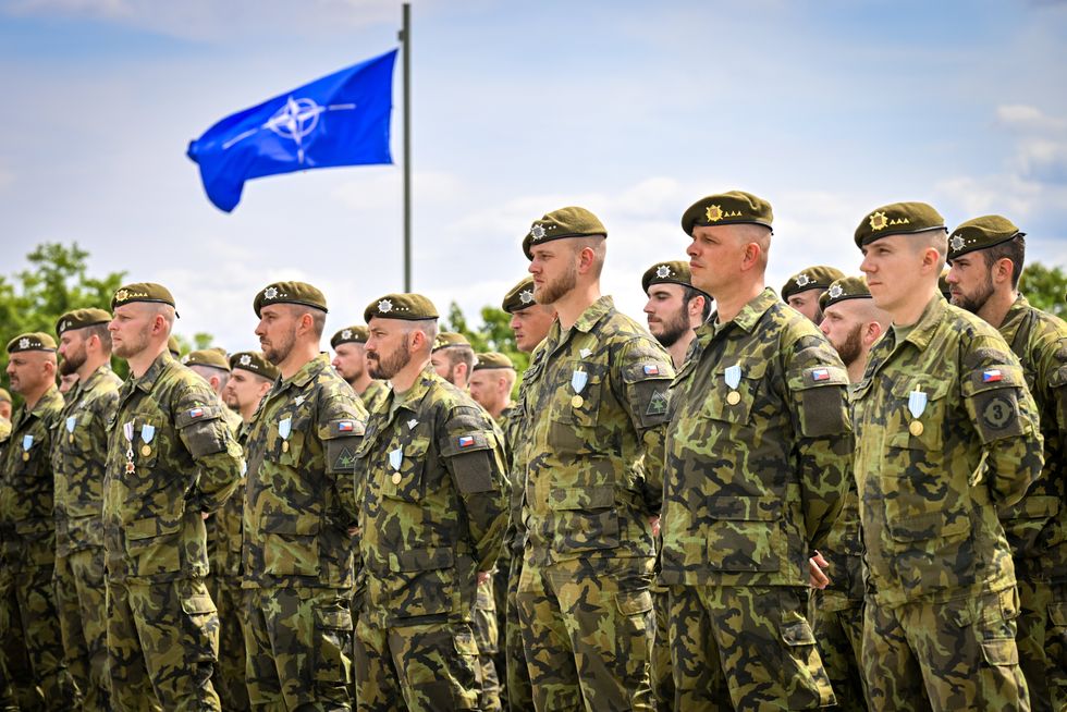photo of czech soldiers in military fatigues with a NATO flag in background