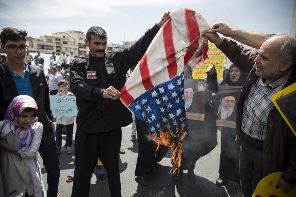 Photo of demonstrators burning a U.S. flag during a 2019 protest supporting Iran's decision to pull out from some part of nuclear deal, in Tehran, Iran, 2019.