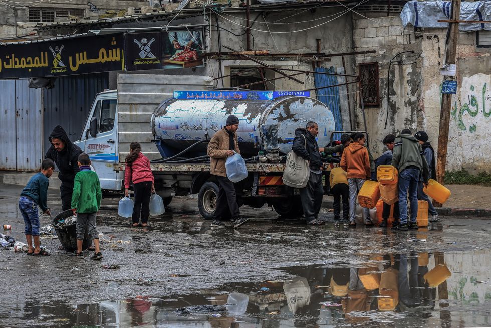 Photo of displaced Palestinians holding jerry cans to fill them with drinking water in Rafah on Feb. 19