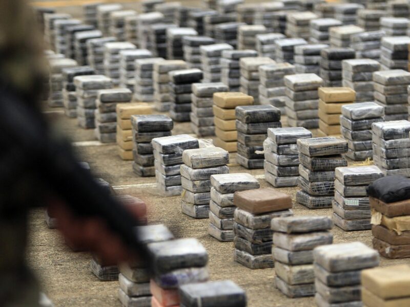 Photo of drugs being guarded by a soldier after a major bust at the border between Colombia and Panama