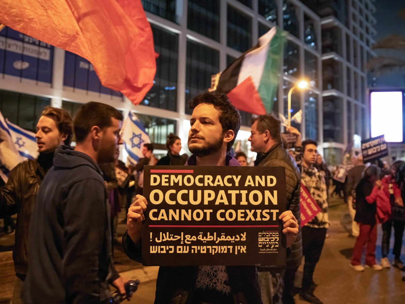 Photo of ​A protestor holding a sign against the Israeli occupation in the West Bank during a demonstration against the judicial reform in Tel Aviv, Israel, in March 2023.