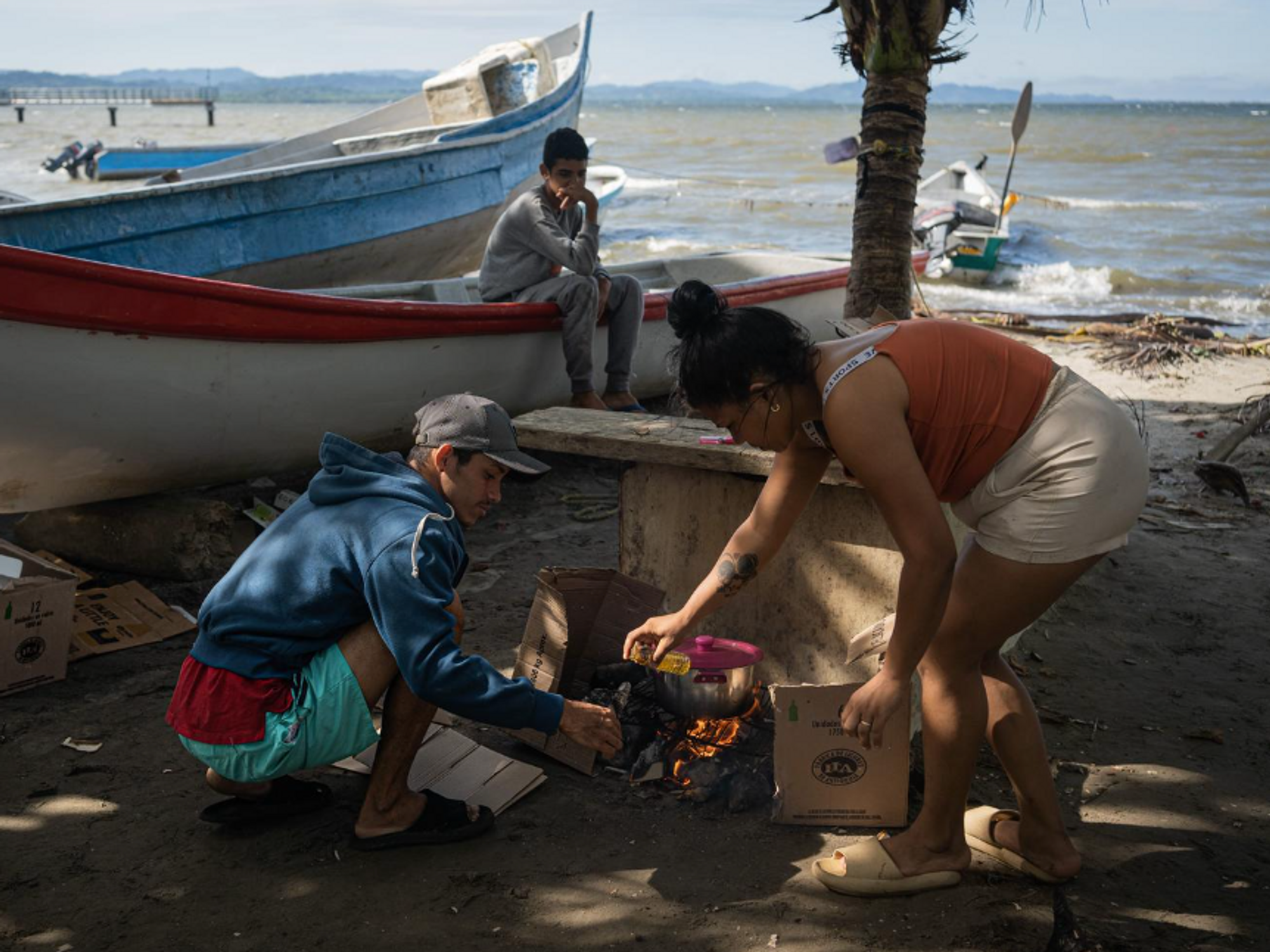 Photo of ​Cheo and Ariana, two migrants hailing from Venezuela, cooking by boats in Necocli.