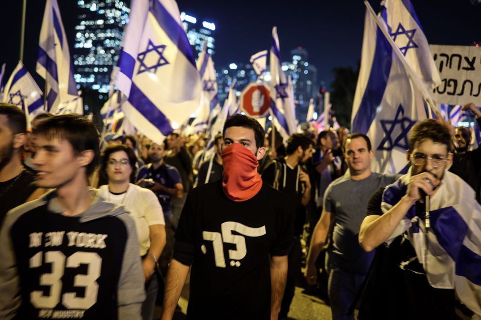 Photo of ​people waving Israeli flags during a protest against Prime Minister Benjamin Netanyahu's planned overhaul of the legal system in March 2023.