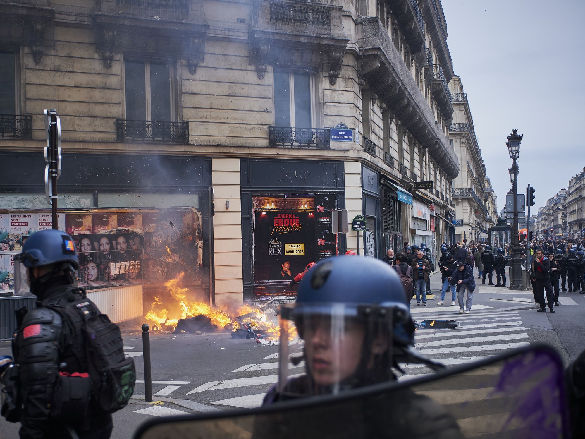 Photo of ​police forces in riot gear clashing with demonstrators as piles of garbage burn in Paris on March 23