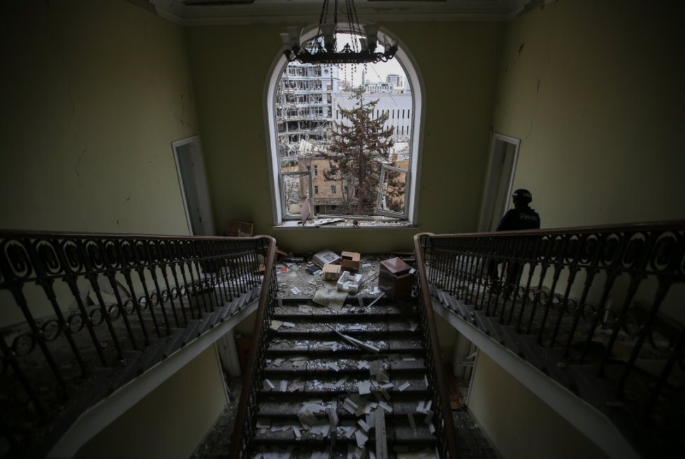 Photo of ​Ukrainian police member going down stairs lined with rubble while on patrol in abandoned building in Kharkiv