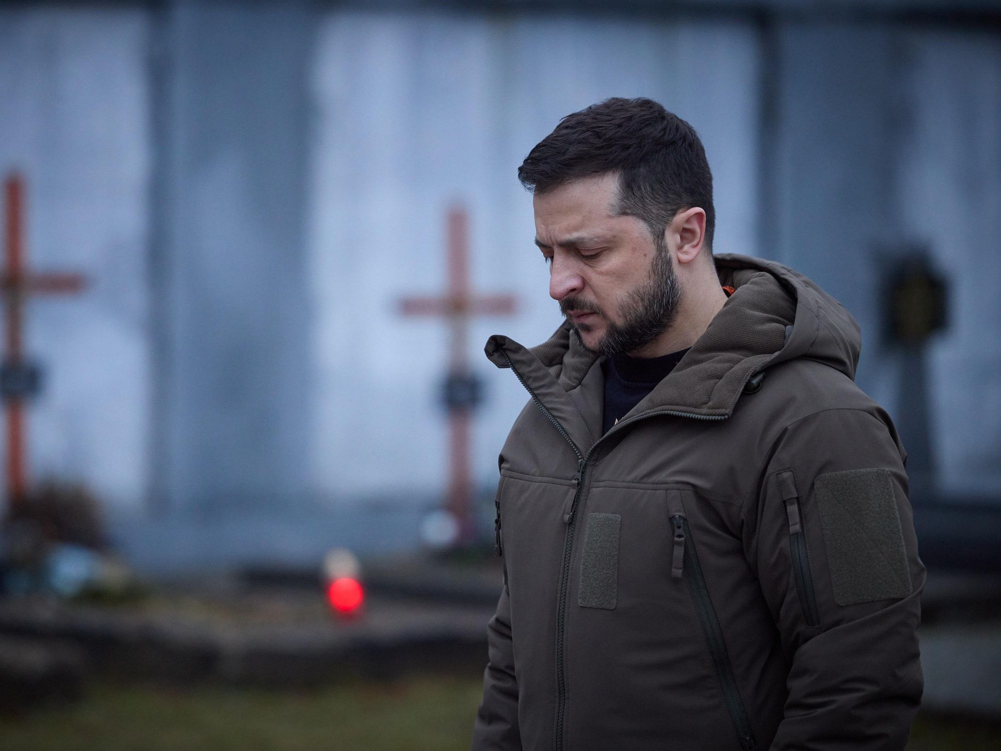Photo of ​Ukrainian President Volodymyr Zelensky looking down in a cemetery in Lviv on Jan. 11