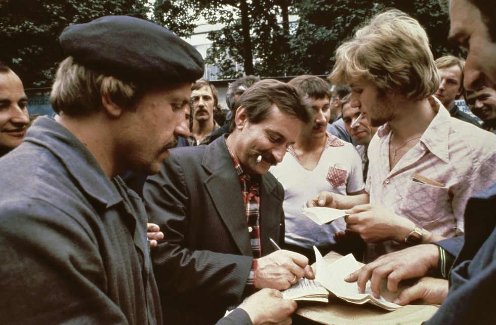 Photo of ​Wałęsa signing autographs during the strike in August 1980.