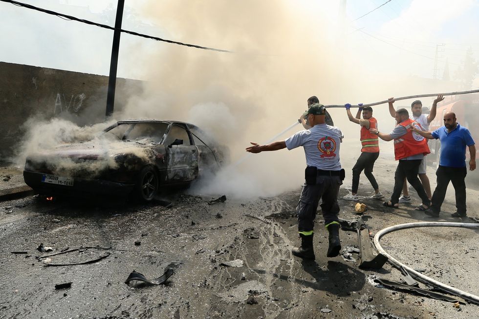 photo of emergency workers putting out a car fire.